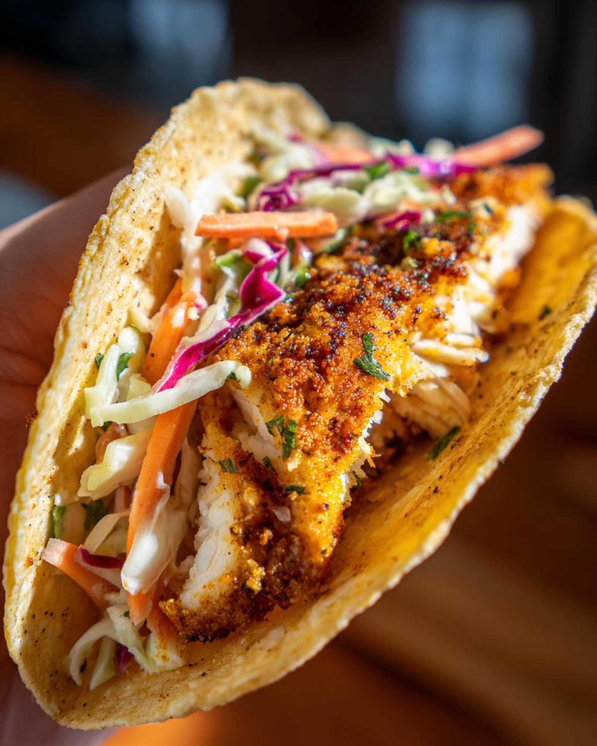 A close-up of a delicious Air Fryer Fish Taco filled with flaky white fish, colorful slaw, and a crispy tortilla.