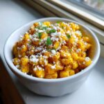 A white bowl filled with delicious Air Fryer Mexican Street Corn, topped with crumbled cheese and cilantro.