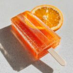 A refreshing Aperol Spritz popsicle with an orange slice, perfect for a summer treat.