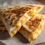 Close-up of two triangular Apple Cheddar Quesadillas, showing the melted cheese and apple filling.