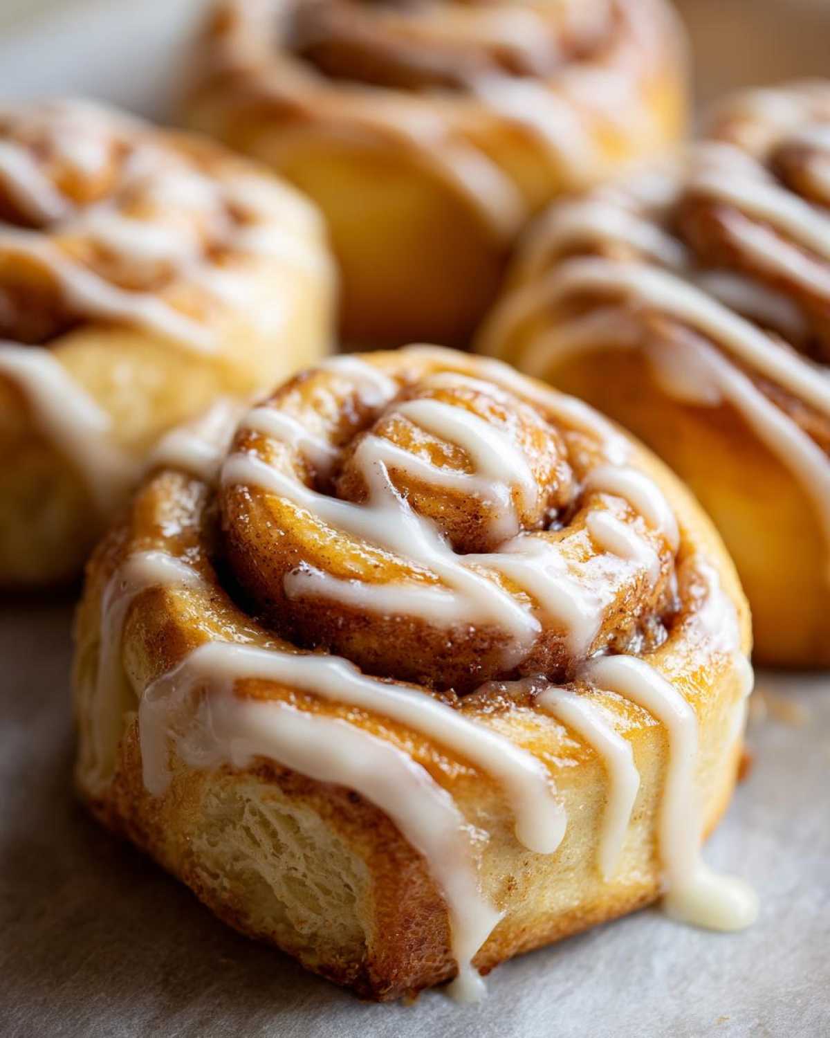 Close-up of a fluffy Apple Cinnamon Roll drizzled with white icing.