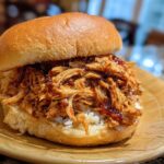 A delicious BBQ Pulled Jackfruit Sandwich on a bun, filled with shredded jackfruit coated in BBQ sauce.
