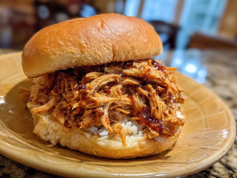 A delicious BBQ Pulled Jackfruit Sandwich on a bun, filled with shredded jackfruit coated in BBQ sauce.