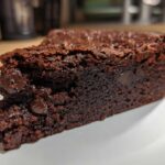 A close-up of a fudgy slice of Black Bean Brownies, showcasing a rich chocolate texture and embedded chocolate chips.