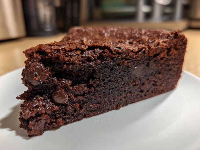 A close-up of a fudgy slice of Black Bean Brownies, showcasing a rich chocolate texture and embedded chocolate chips.