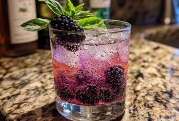 A refreshing Blackberry Basil Gin Smash cocktail with fresh blackberries and basil garnish in a glass with ice.