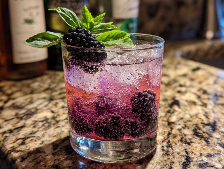 A refreshing Blackberry Basil Gin Smash cocktail with fresh blackberries and basil garnish in a glass with ice.