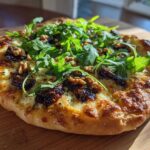A delicious Blue Cheese & Fig Flatbread topped with fresh arugula and walnuts on a wooden board.