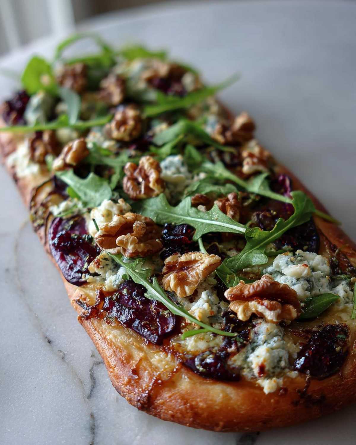 A close-up of a Blue Cheese & Fig Flatbread topped with crumbled blue cheese, figs, walnuts, and fresh arugula.