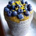 A close-up of Blueberry Lemon Chia Pudding in a jar, topped with fresh blueberries and lemon zest.
