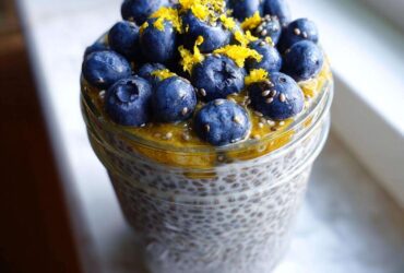 A close-up of Blueberry Lemon Chia Pudding in a jar, topped with fresh blueberries and lemon zest.