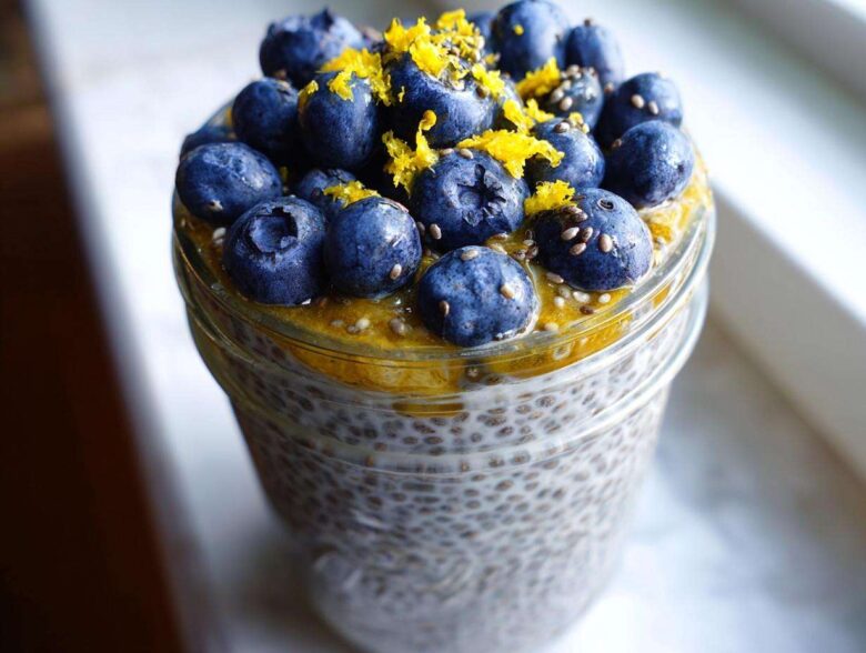A close-up of Blueberry Lemon Chia Pudding in a jar, topped with fresh blueberries and lemon zest.