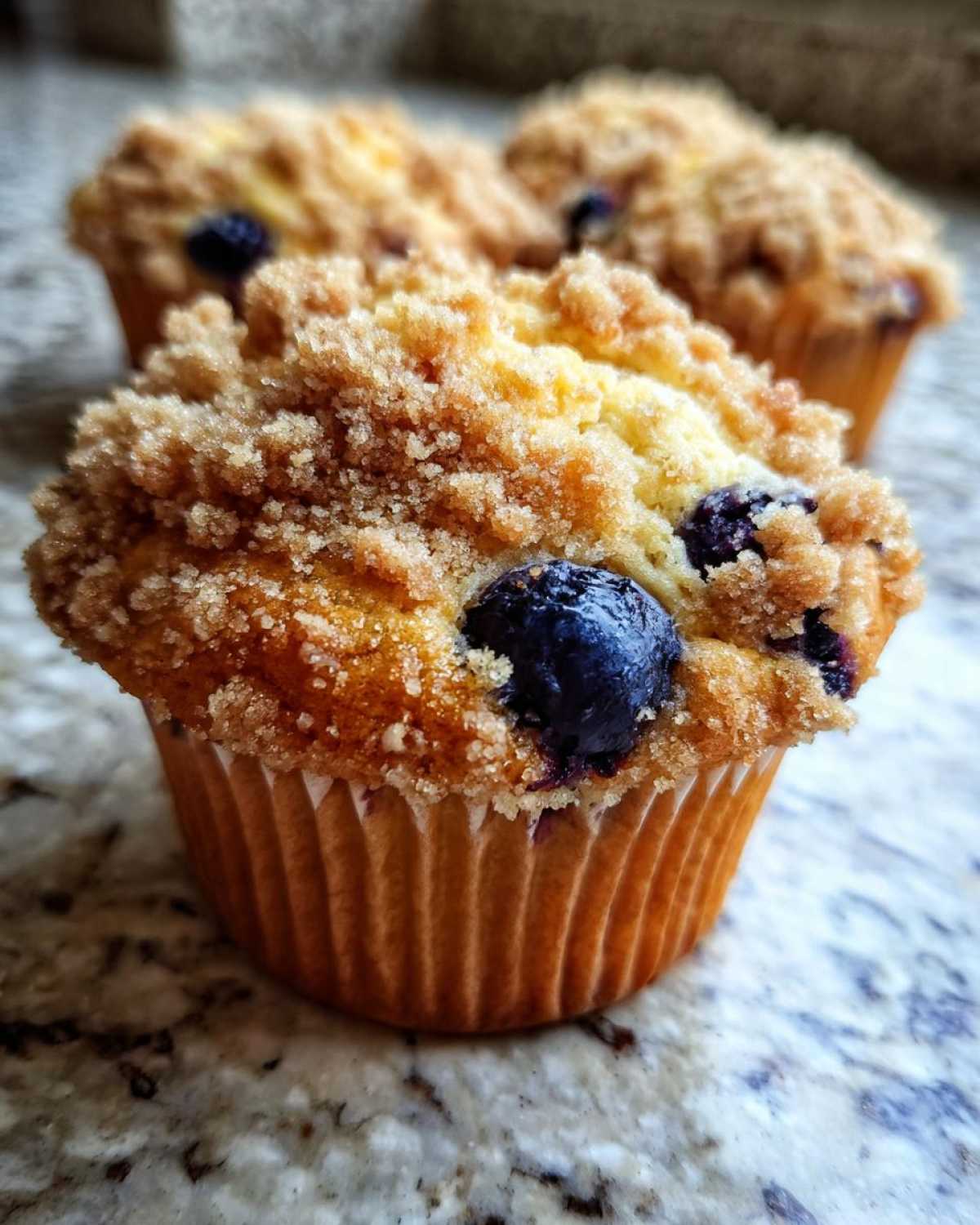 Close-up of a delicious blueberry streusel muffin with a golden brown streusel topping and fresh blueberries.