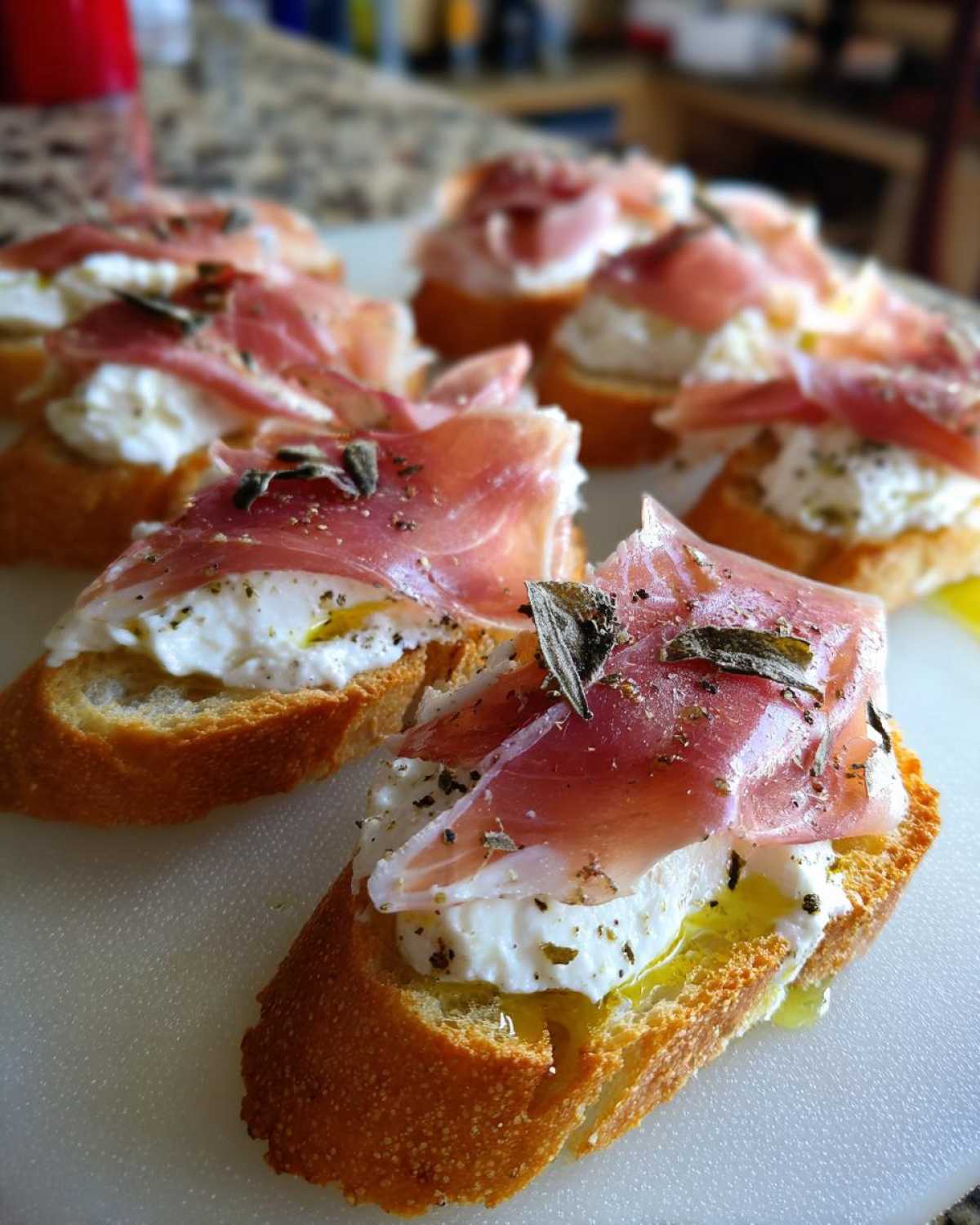 Close-up of delicious Burrata & Prosciutto Crostini, featuring creamy burrata cheese, thinly sliced prosciutto, and fresh herbs on toasted baguette slices.