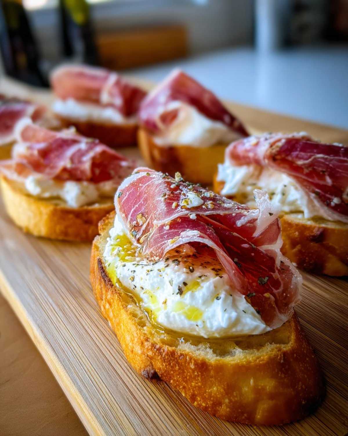 Close-up of delicious Burrata & Prosciutto Crostini on a wooden board, drizzled with olive oil and herbs.