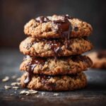 A stack of delicious Chocolate Chip Oatmeal Cookies with melted chocolate drizzling down.