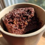 Close-up of a rich Chocolate Orange Mug Cake in a tan mug, topped with chocolate sprinkles.
