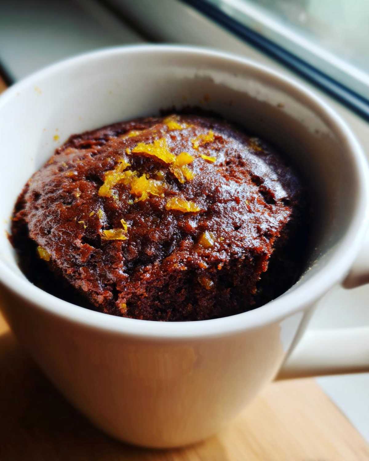 Close-up of a rich Chocolate Orange Mug Cake topped with orange zest in a white mug.