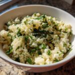 A white bowl filled with freshly prepared Cilantro Lime Cauliflower Rice, garnished with chopped cilantro.