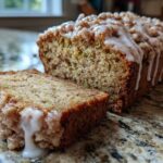 A slice of moist cinnamon streusel topped zucchini bread with a drizzle of glaze.