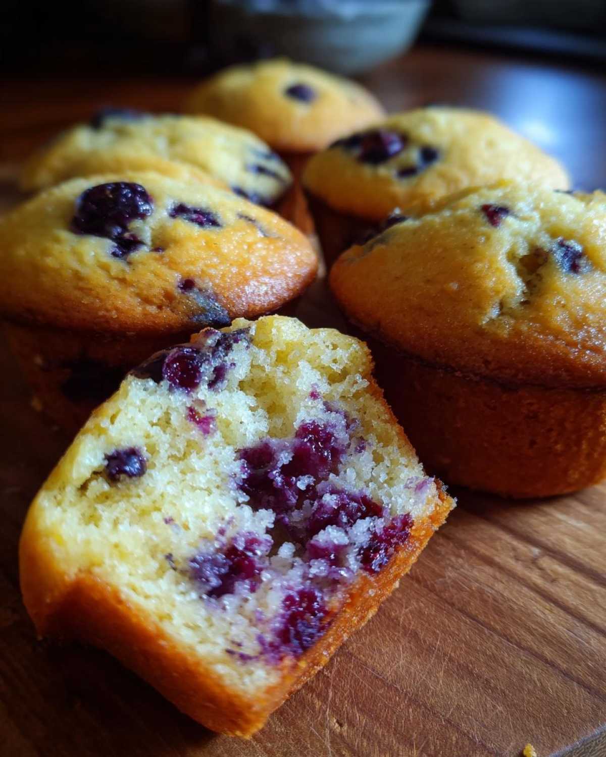 A close-up of a classic blueberry muffin, cut in half to reveal a moist interior packed with blueberries.