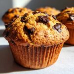 Close-up of a freshly baked classic chocolate chip muffin with visible chocolate chunks.
