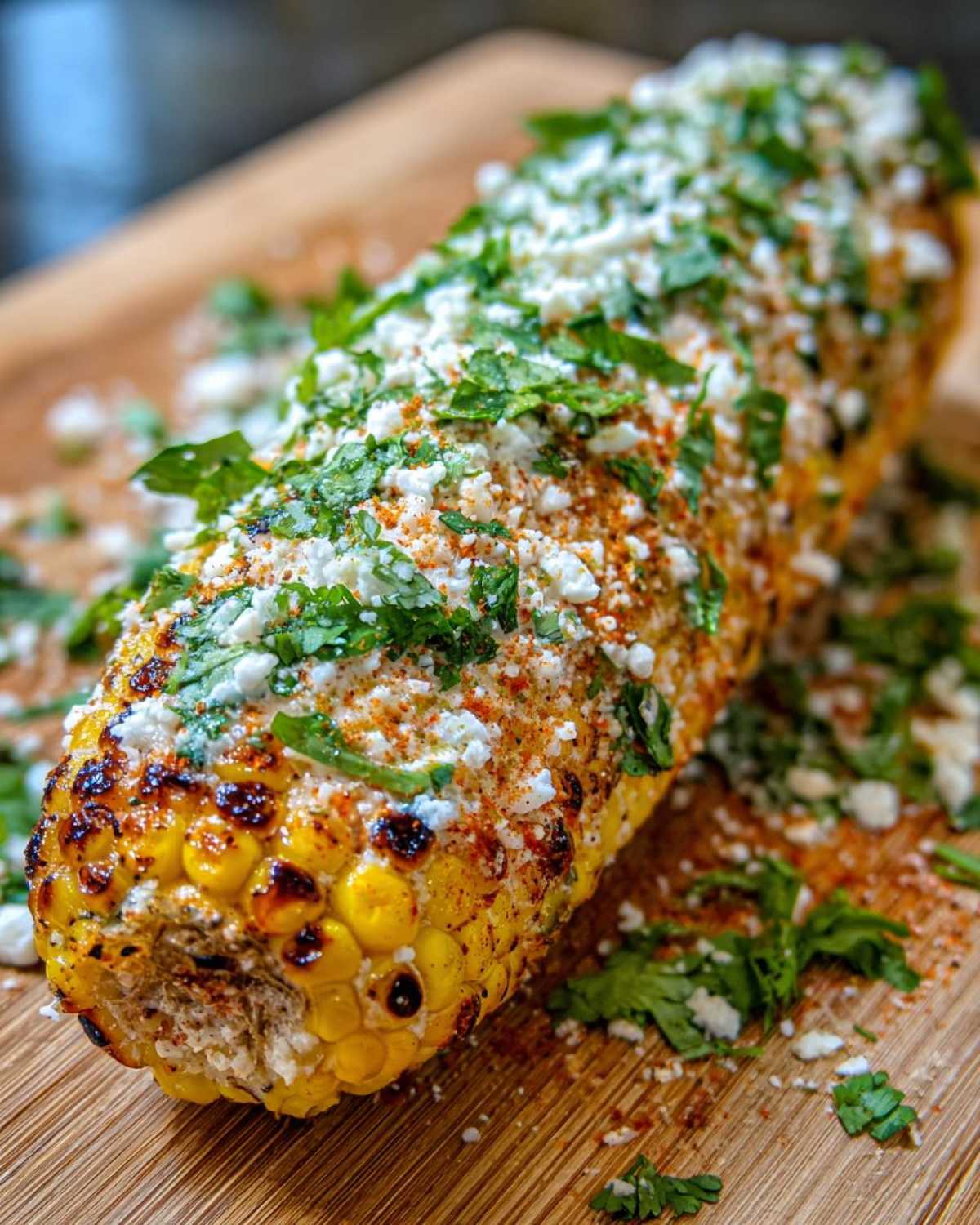 Close-up of a grilled ear of corn, coated in cheese, chili powder, and cilantro, showcasing the perfect Elote recipe.