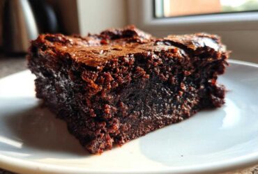 A close-up of a rich, fudgy espresso brownie slice on a white plate, showcasing its moist texture.
