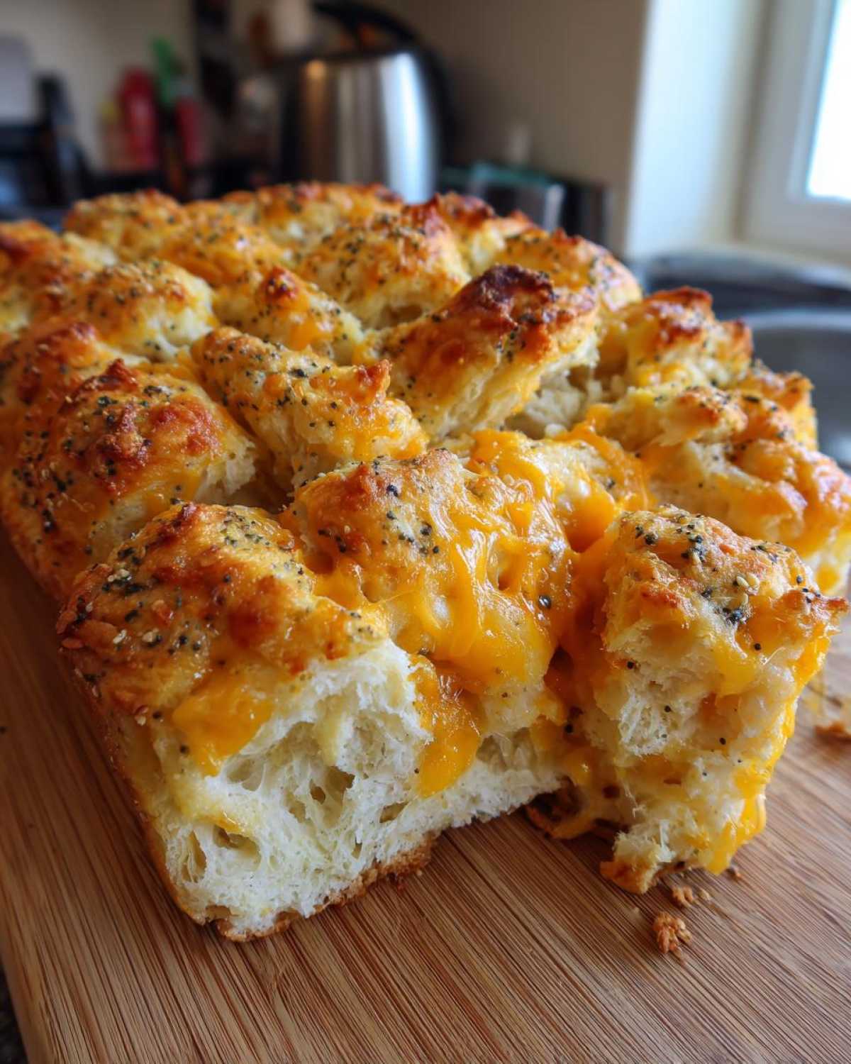 A close-up of a golden-brown Everything Bagel Pull Apart Loaf, with melted cheese oozing out.