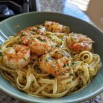 A close-up of Garlic Herb Shrimp Scampi served over linguine pasta in a teal bowl.