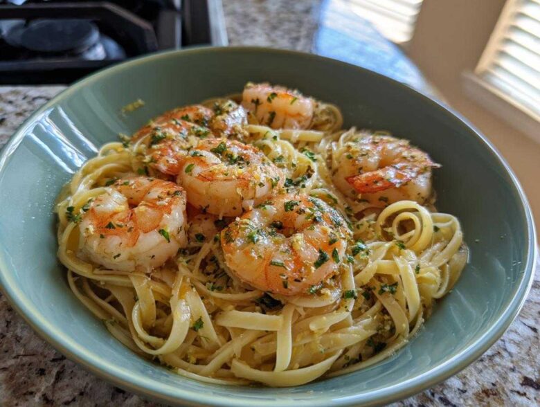 A close-up of Garlic Herb Shrimp Scampi served over linguine pasta in a teal bowl.