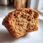 A close-up view of a moist and fluffy gluten-free pumpkin muffin, showing its crumbly texture.