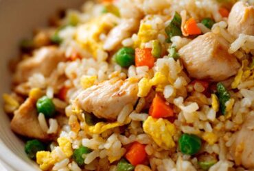 A close-up of a bowl filled with flavorful Hibachi Chicken Fried Rice, featuring tender chicken pieces, fluffy rice, peas, carrots, and scrambled egg.