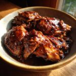 Close-up of tender Instant Pot Balsamic Chicken pieces coated in a rich, glossy sauce in a rustic bowl.