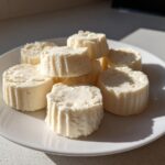 A white plate filled with several round Keto Cheesecake Fat Bombs, showing their textured sides.