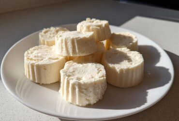 A white plate filled with several round Keto Cheesecake Fat Bombs, showing their textured sides.