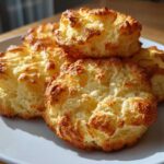 A close-up of fluffy, golden-brown Keto Cloud Bread puffs piled on a white plate.