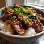 A close-up of a Korean Beef Bowl (Bulgogi) with tender marinated beef slices over white rice, topped with sesame seeds and chopped green onions.