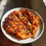A close-up of crispy Korean Kimchi Pancakes (Pajeon) cut into strips and served on a white plate.