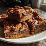 A stack of delicious Maple Pecan Swirl Blondies topped with whole pecans on a white plate.