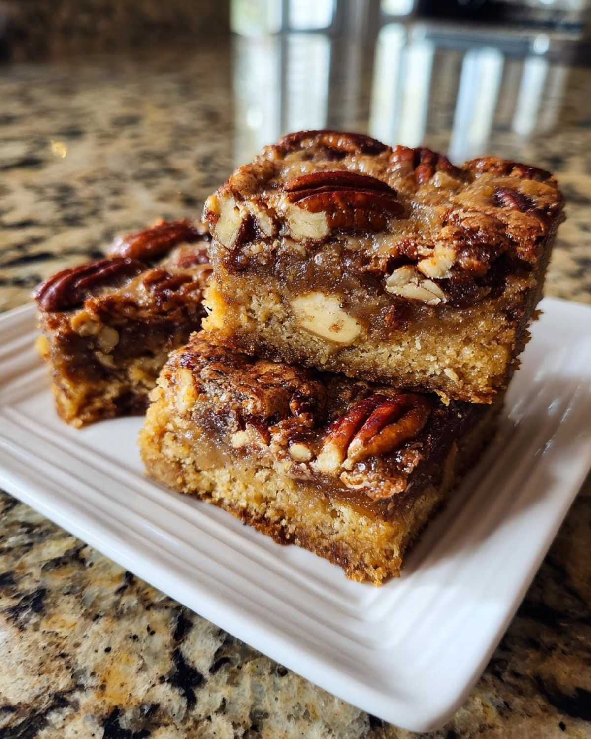 A stack of three delicious Maple Pecan Swirl Blondies topped with whole pecans.