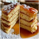 A stack of fluffy Maple Soufflé Pancakes drizzled with maple syrup and dusted with powdered sugar.