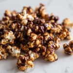A close-up shot of a pile of fluffy popcorn generously coated with rich mocha drizzle.