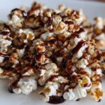 A close-up of fluffy popcorn drizzled with rich mocha sauce, a perfect sweet and salty treat.