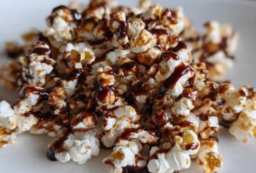 A close-up of fluffy popcorn drizzled with rich mocha sauce, a perfect sweet and salty treat.