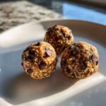 Three delicious Oatmeal Chocolate Chip Energy Bites arranged on a white plate, showcasing visible oats and chocolate chips.