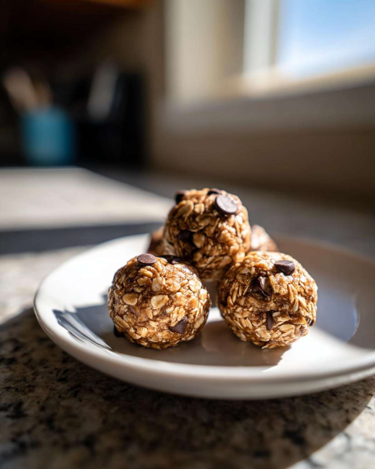 Close-up of delicious Oatmeal Chocolate Chip Energy Bites on a white plate, with chocolate chips visible.