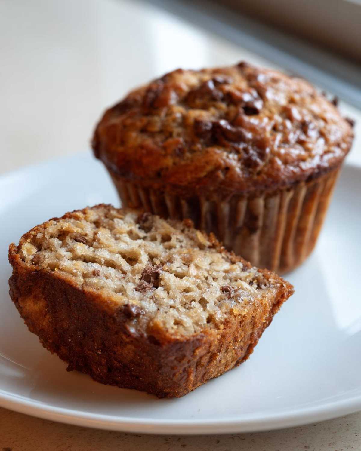 A close-up view of a sliced Oatmeal Chocolate Chip Muffin, revealing texture and chocolate chips.