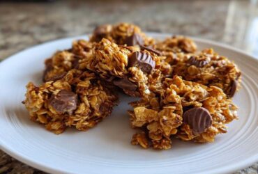 Close-up of delicious Peanut Butter Cup Granola clusters on a white plate, featuring oats and chunks of peanut butter cups.