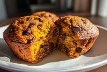A close-up view of a broken Pumpkin Chocolate Chip Muffin, revealing its moist interior and chocolate chips.